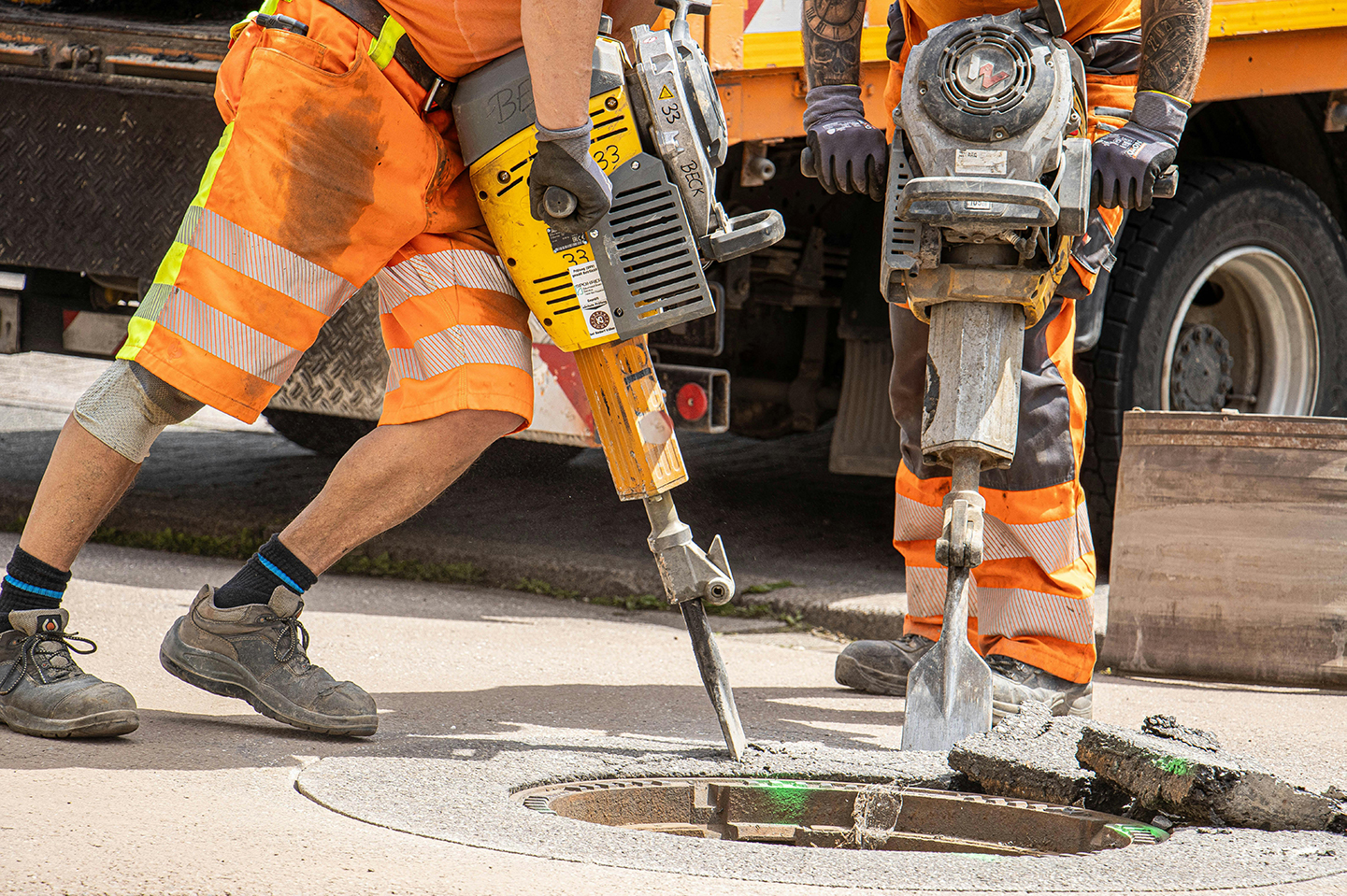 Construction workers using a jackhammer on a street.